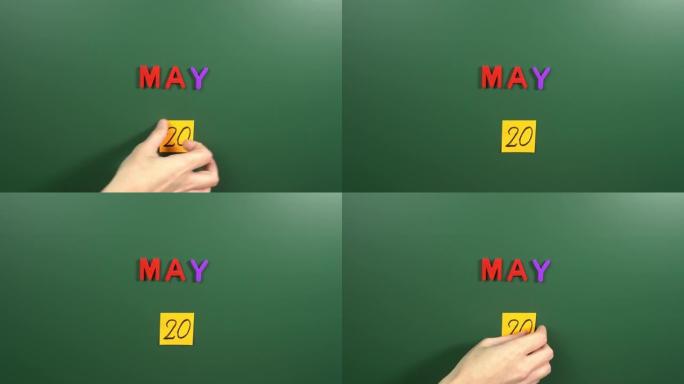 5月20日日历日用手在学校董事会上贴一张贴纸。5月20日。5月20日。第20个日期号。20天日历。二