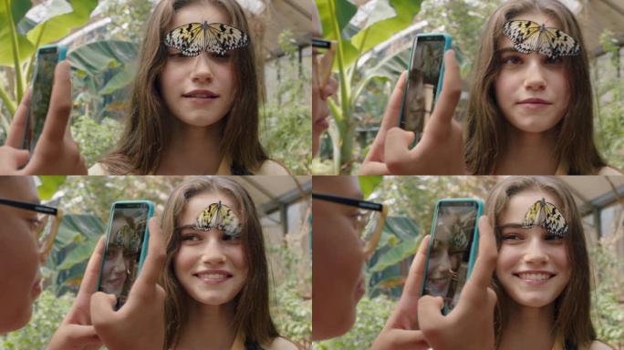 女孩脸上美丽的蝴蝶与快乐的朋友用智能手机拍照朋友在动物园野生动物保护区玩得开心在社交媒体上分享自然游