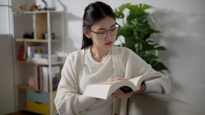 亚洲年轻女子在家客厅阅读教科书
