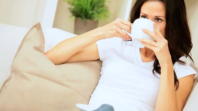女性在家庭沙发上喝咖啡