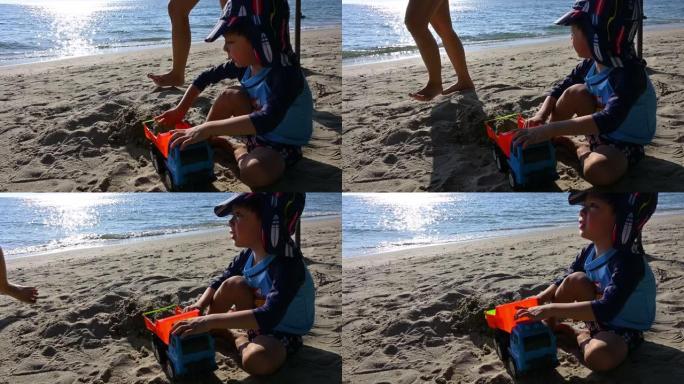 手持镜头，玩玩具自卸车的快乐孩子在假期的沙滩上玩得开心