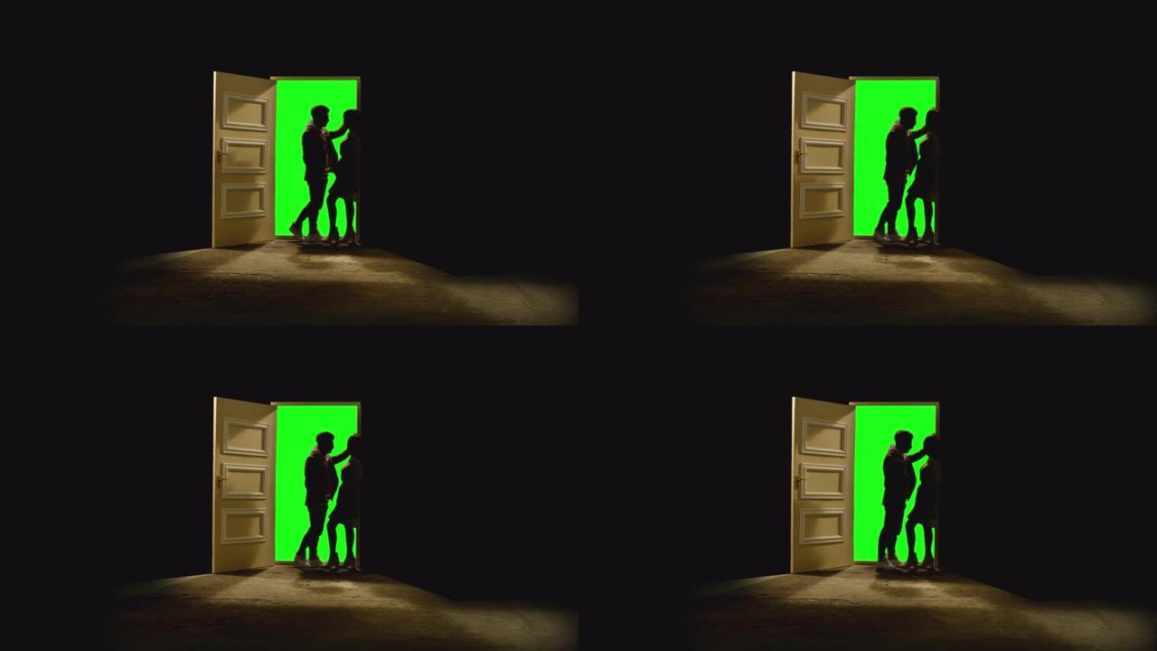 4k侧视图，夫妇站在对面，在敞开的门前互相注视，后面是黑暗。一对夫妇的镜头站在靠近门的地板上，绿屏。