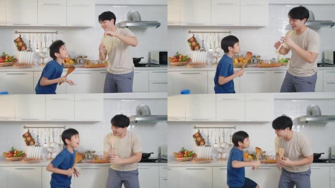 亚洲父子一边做饭，一边在家里的厨房里快乐地跳舞。单身父亲概念