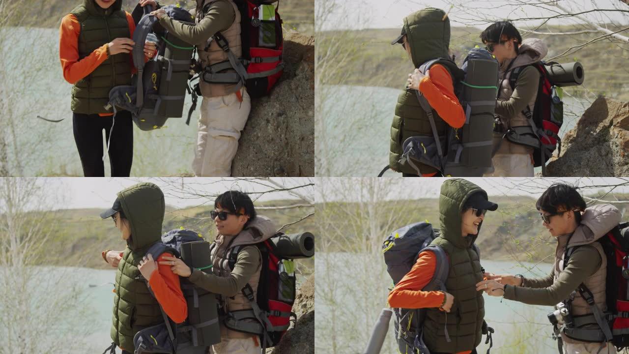 在岩石海岸上的两名亚洲女性游客，其中一名帮助其他人将背囊