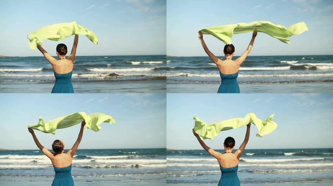 女人挥舞着纱笼站在沙滩上，慢动作