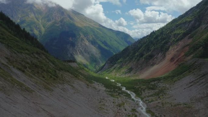 在云雾覆盖的山峰之间流动的山流的鸟瞰图。