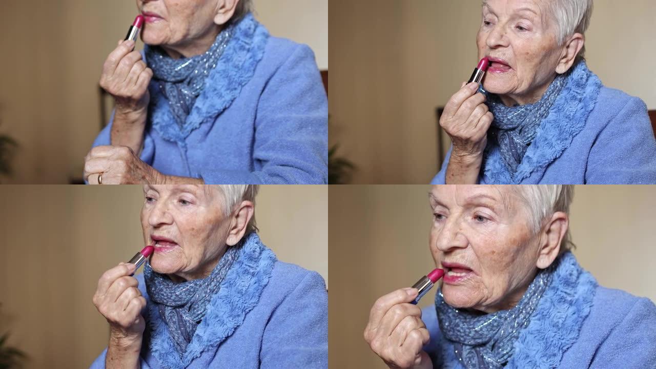 白发蓝眼睛的老年妇女用口红涂嘴唇。化妆和衰老概念。老年人的健康和福祉。手握红色唇彩