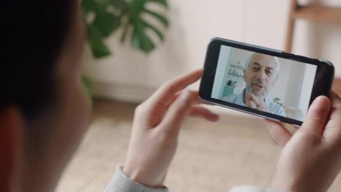 年轻女子使用智能手机视频聊天，与聋哑祖父使用手语手势交流，享受在线交流
