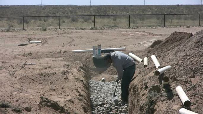 工人在排水场平整石块以进行化粪池