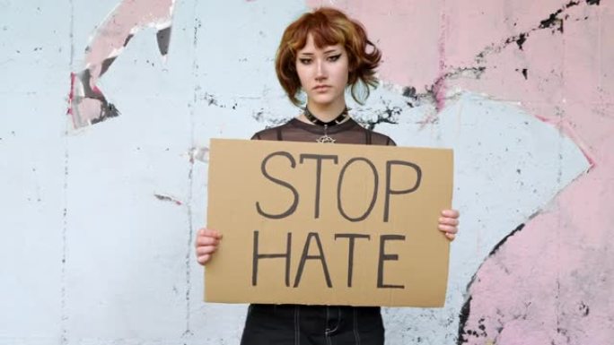 亚洲少女手持写有“STOP HATE”纸板的标志，作为阻止威胁和犯罪的象征。抗议活动。另类的青春。学