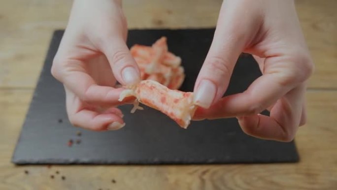 女孩用手拿一块蟹肉，对着镜头看。