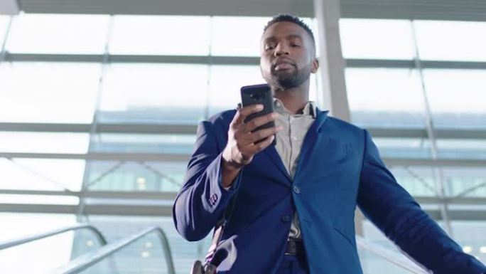 年轻的非洲裔美国商人在自动扶梯上使用智能手机发短信在网上查看电子邮件在公司办公室成功的男性主管离开工