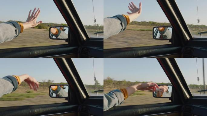女人牵着手走出车窗，感觉风吹过手指，在乡下开车，暑假旅行，享受路上的自由