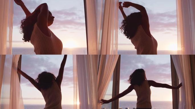 快乐的女人举起手臂，在家里享受清晨的日出，在假期放松，看着美丽的海景