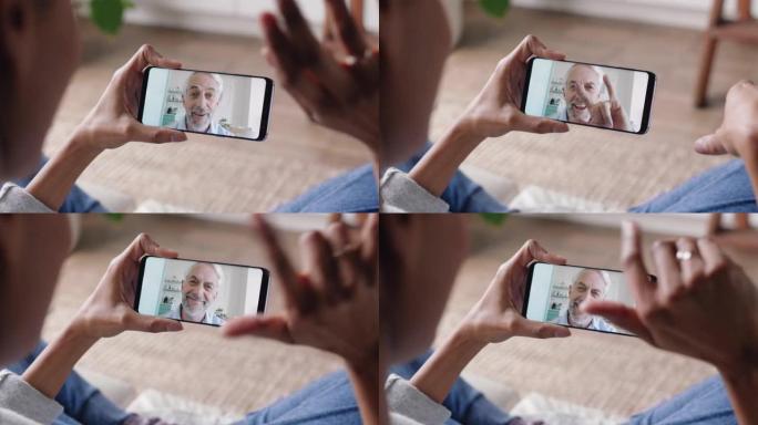 年轻女子使用智能手机视频聊天，与聋哑祖父使用手语手势交流，享受在线交流