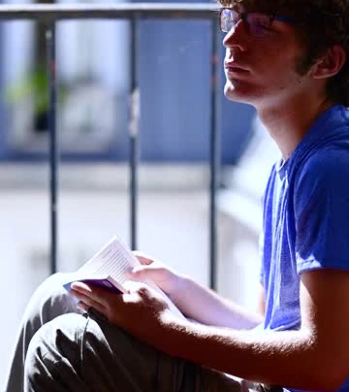 一个年轻的高加索人坐在阁楼的窗户旁，看书放松。背景模糊。放松，休闲，反思，无忧无虑，学习和青春的概念