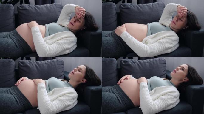 对分娩概念感到恐惧。特写疲惫的年轻孕妇患头痛或消极想法，担心不好的产前筛查结果，躺在家里的沙发上