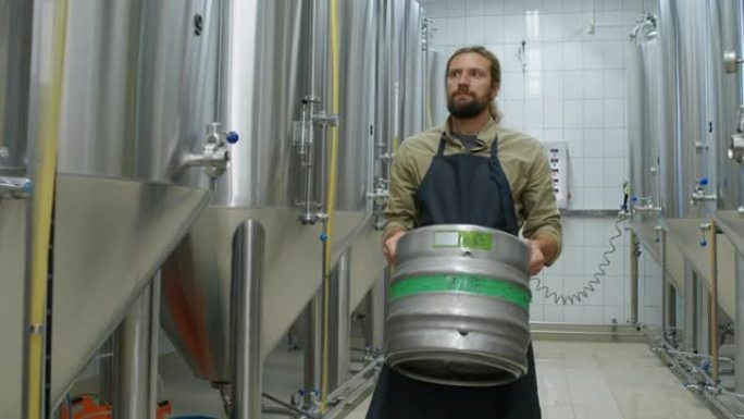 高加索男性雇员在啤酒厂携带重啤酒桶