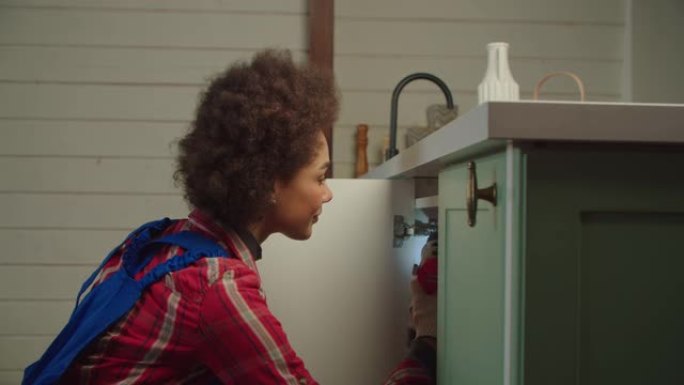 非裔美国DIY女士用电动螺丝刀修理厨柜