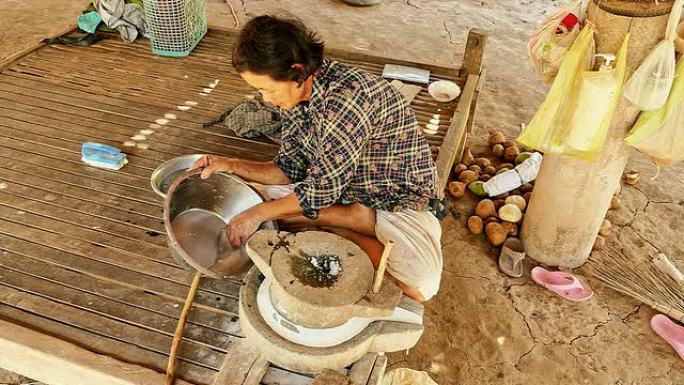 女人用手翻磨石磨湿米饭做浸泡米粉