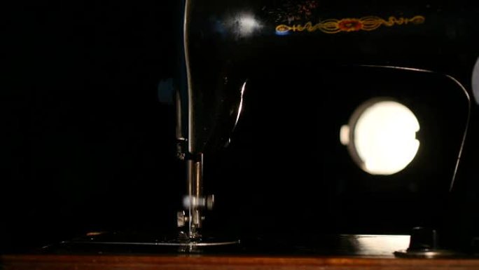 黑色背景上的古董工作深色、棕色和银色缝纫机，背光