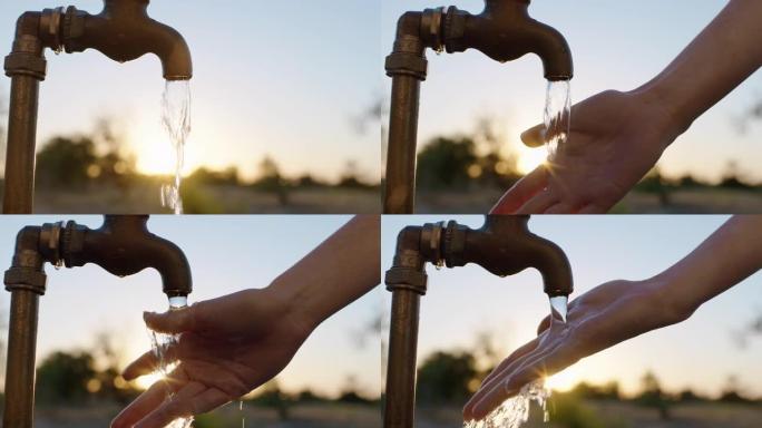 日出时，关闭妇女在农村农田用淡水在水龙头下洗手
