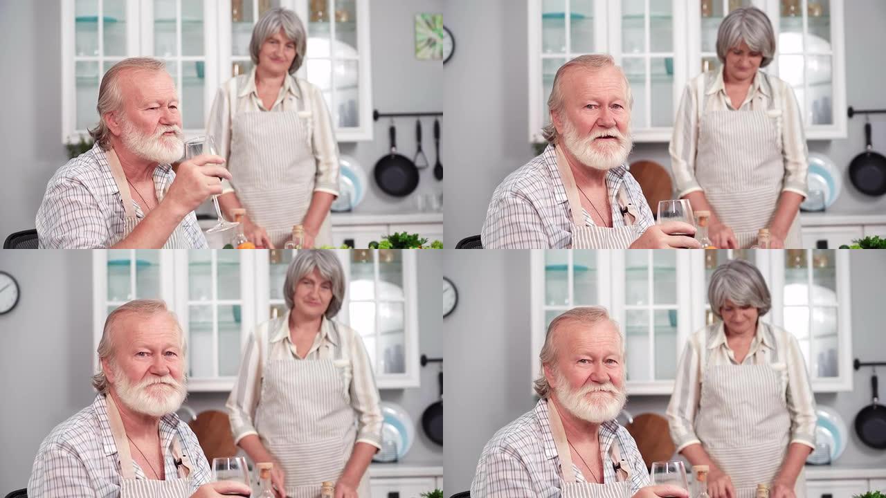 一个老人喝葡萄酒的肖像，一个有爱心的妻子在厨房里准备家庭晚餐，看着相机