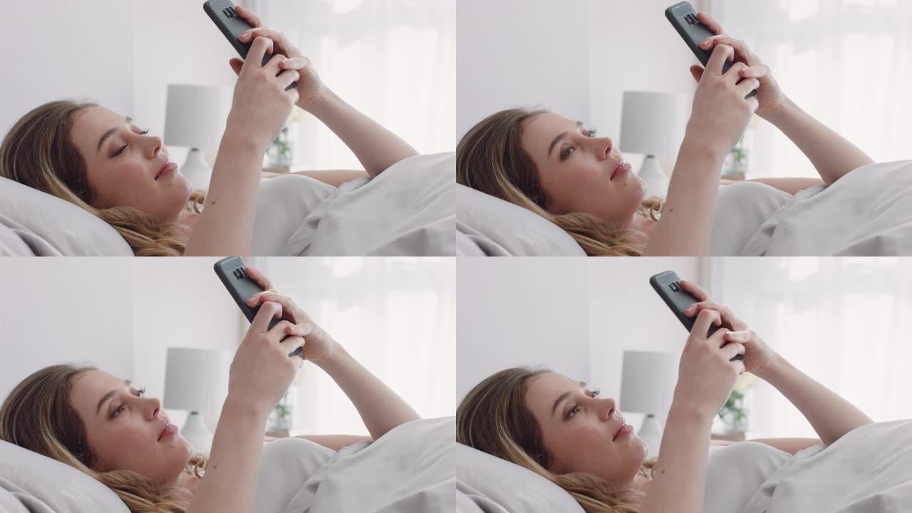 美丽的女人使用智能手机发短信躺在床上浏览社交媒体信息享受分享放松的周末在家