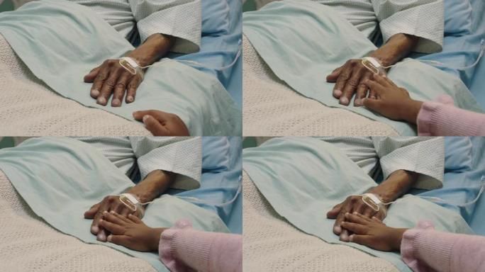 小女孩触摸祖父的手躺在医院的病床上，孩子在床边对祖父母从疾病中康复表示爱意。医疗保健家庭支持