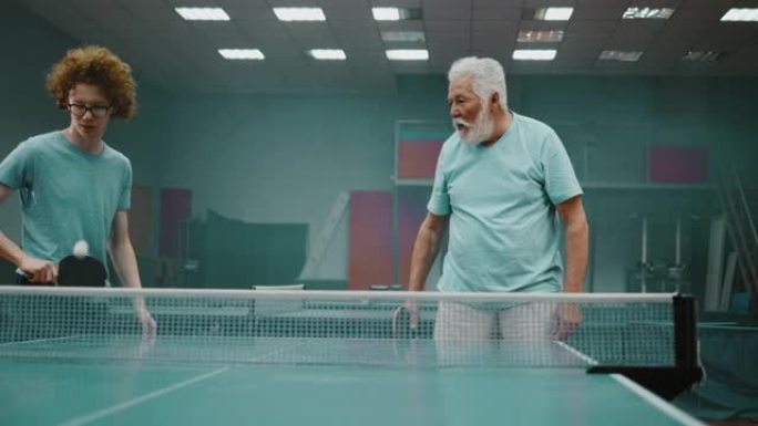 70年代的祖父和他的十几岁的孙子打乒乓球，丢了一分