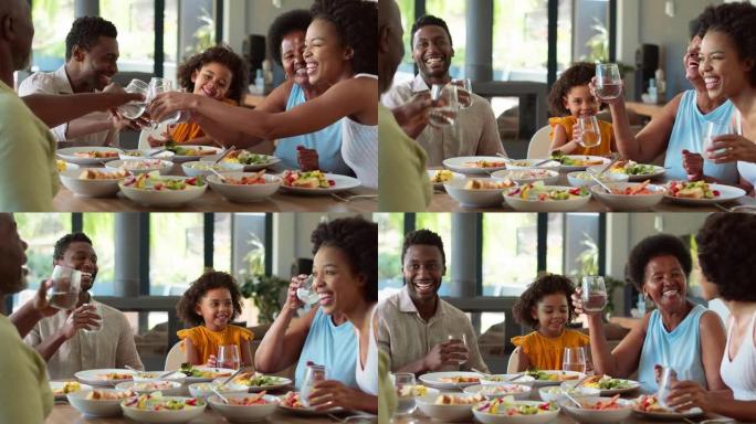 多代家庭在餐桌旁喝水欢呼，然后在家用餐