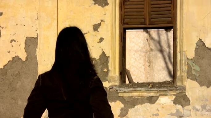 女孩看着一栋废弃的旧房子