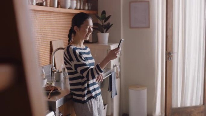 年轻的亚洲女性拿着智能手机视频聊天，在家中用手语和聋哑朋友聊天