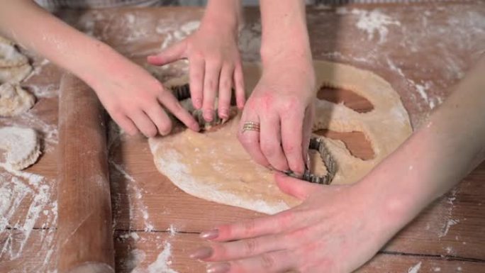 儿童烹饪培训，有爱心的女父母和她的女儿一起在厨房的桌子上用烘焙模具制作面团饼干