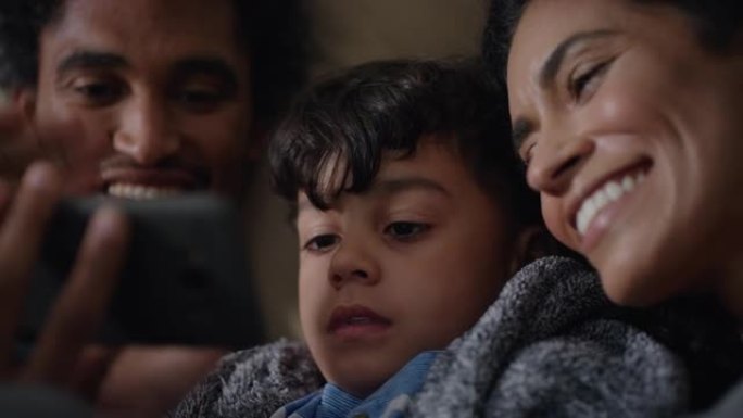 快乐的家庭与小男孩视频聊天，使用智能手机在屏幕上挥舞，在家中享受手机通讯
