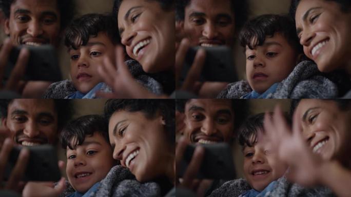 快乐的家庭与小男孩视频聊天，使用智能手机在屏幕上挥舞，在家中享受手机通讯