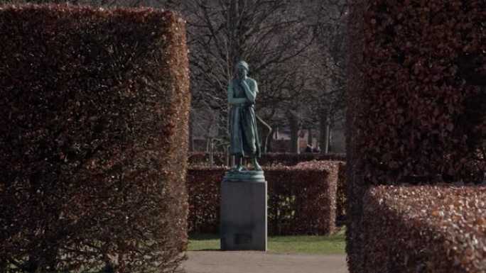 在丹麦哥本哈根的一个公园里，一座美丽的雕像被灌木丛环绕