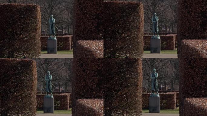 在丹麦哥本哈根的一个公园里，一座美丽的雕像被灌木丛环绕