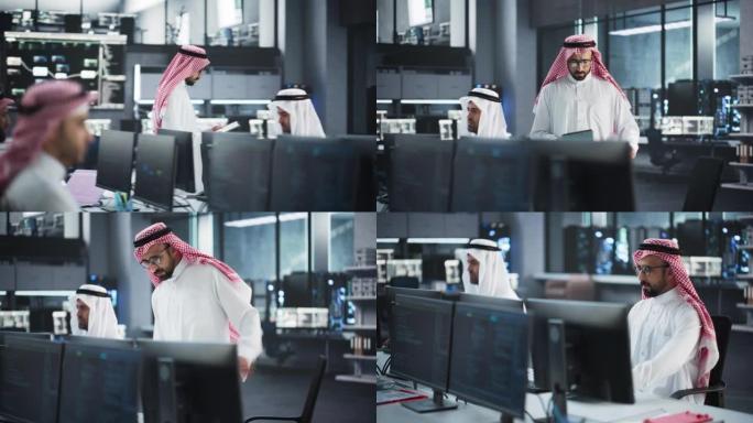 阿拉伯信息和网络安全专家走在办公室里，坐下来在他的台式电脑上工作。穿着传统白袍的年轻中东软件工程师