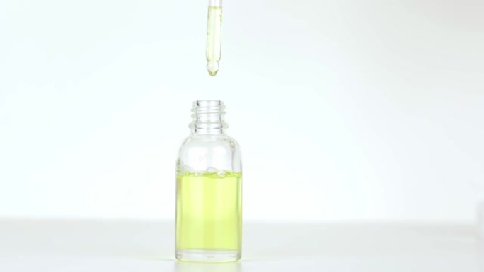 移液器中的一滴油滴入玻璃化妆品瓶中