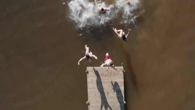鸟瞰图的朋友从湖上跳下码头，玩得开心，在暑假享受自由，从上面看无人机