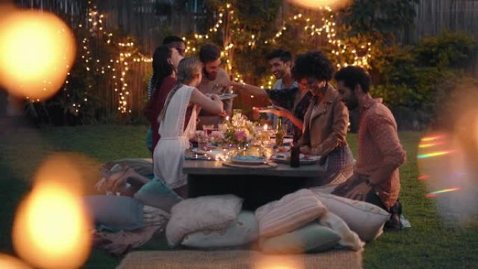 一群年轻的朋友在晚宴上庆祝聊天分享健康食物坐在餐桌上享受周末聚会在美丽的夏日户外4k