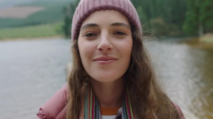 肖像快乐的女人微笑感觉快乐戴着便帽享受寒冷的冬天在大自然的户外湖边真实的人4k