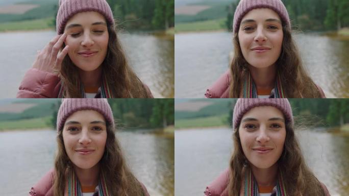 肖像快乐的女人微笑感觉快乐戴着便帽享受寒冷的冬天在大自然的户外湖边真实的人4k