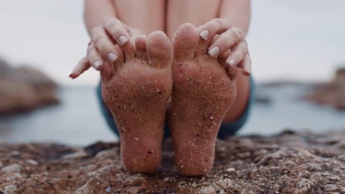 近距离的沙脚年轻女子坐在沙滩上赤脚享受暑假