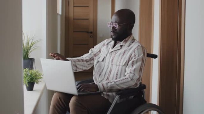 坐在轮椅上的黑人合上笔记本电脑，看着相机