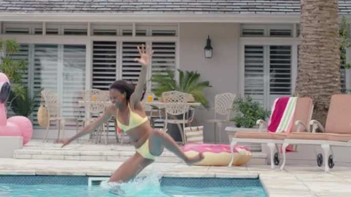 快乐的非洲裔美国妇女跳进游泳池嬉戏玩得开心暑假享受夏天穿着黄色比基尼4k镜头