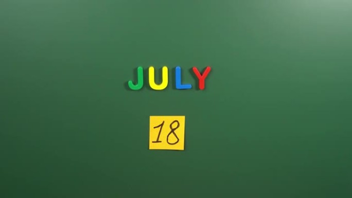 7月18日日历日用手在学校董事会上贴一张贴纸。18 7月日期。7月的第十八天。第18个日期编号。18