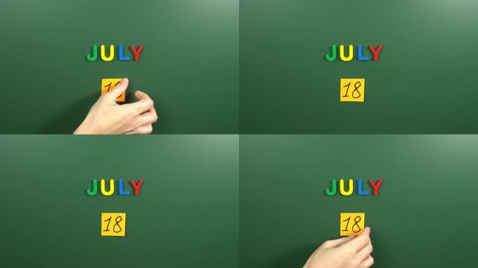 7月18日日历日用手在学校董事会上贴一张贴纸。18 7月日期。7月的第十八天。第18个日期编号。18