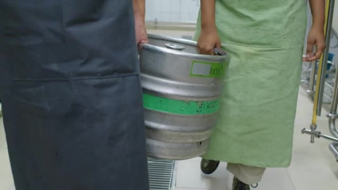 啤酒厂携带重型小桶的匿名男女工人